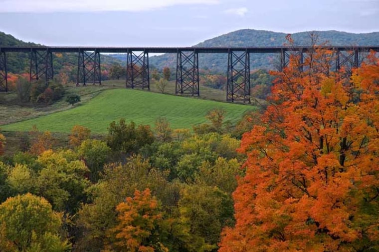 A train bridge in Upper New York state USA set against turning Fall leaves